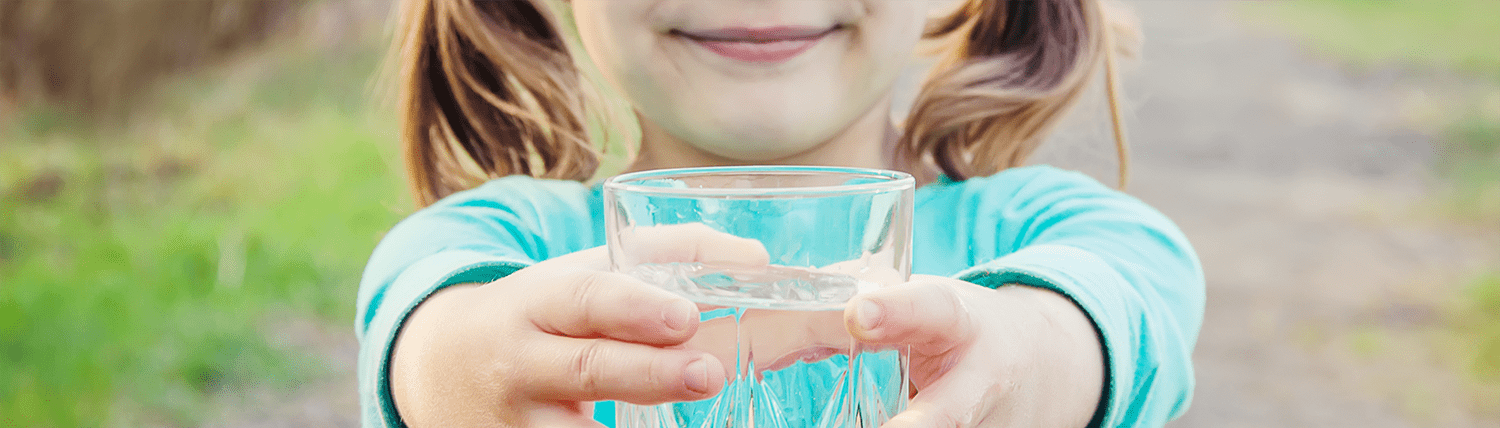 Little girl holds a glass of clean water